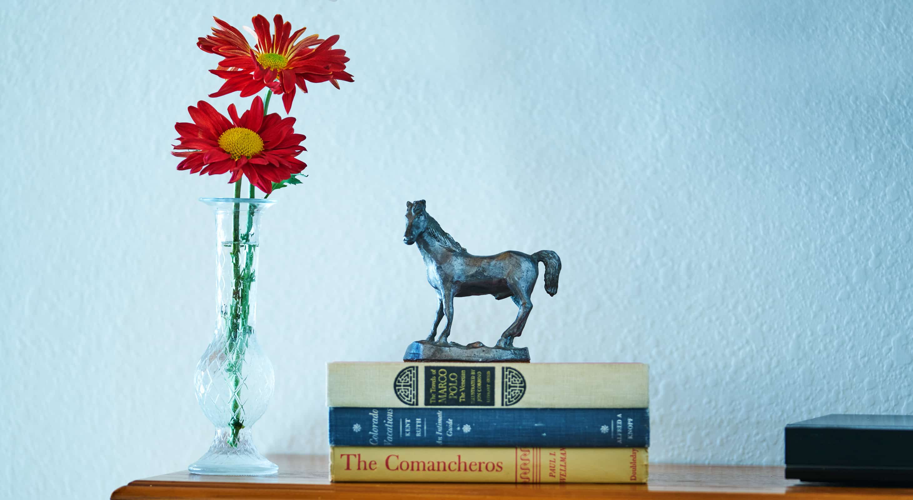 A small flower vase and a stack a books